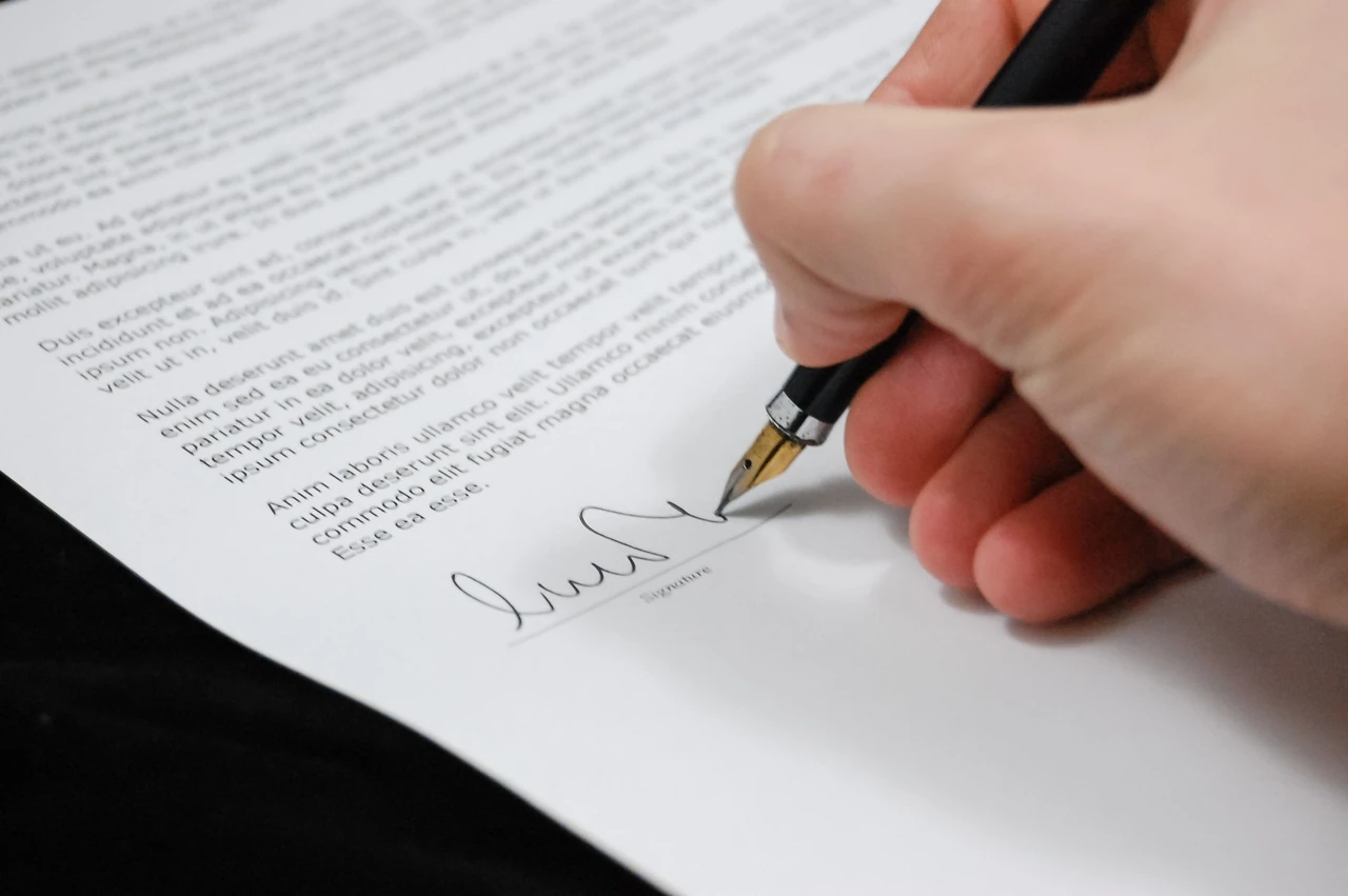 Close-up of a hand signing a printed document with a pen