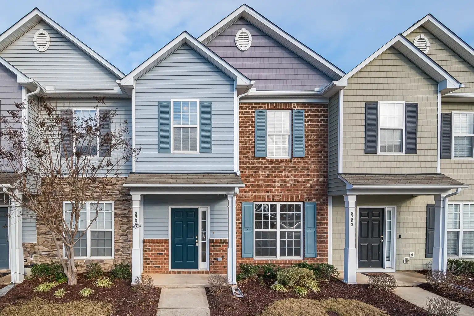 Brick and pastel townhouses with front doors facing a quiet street