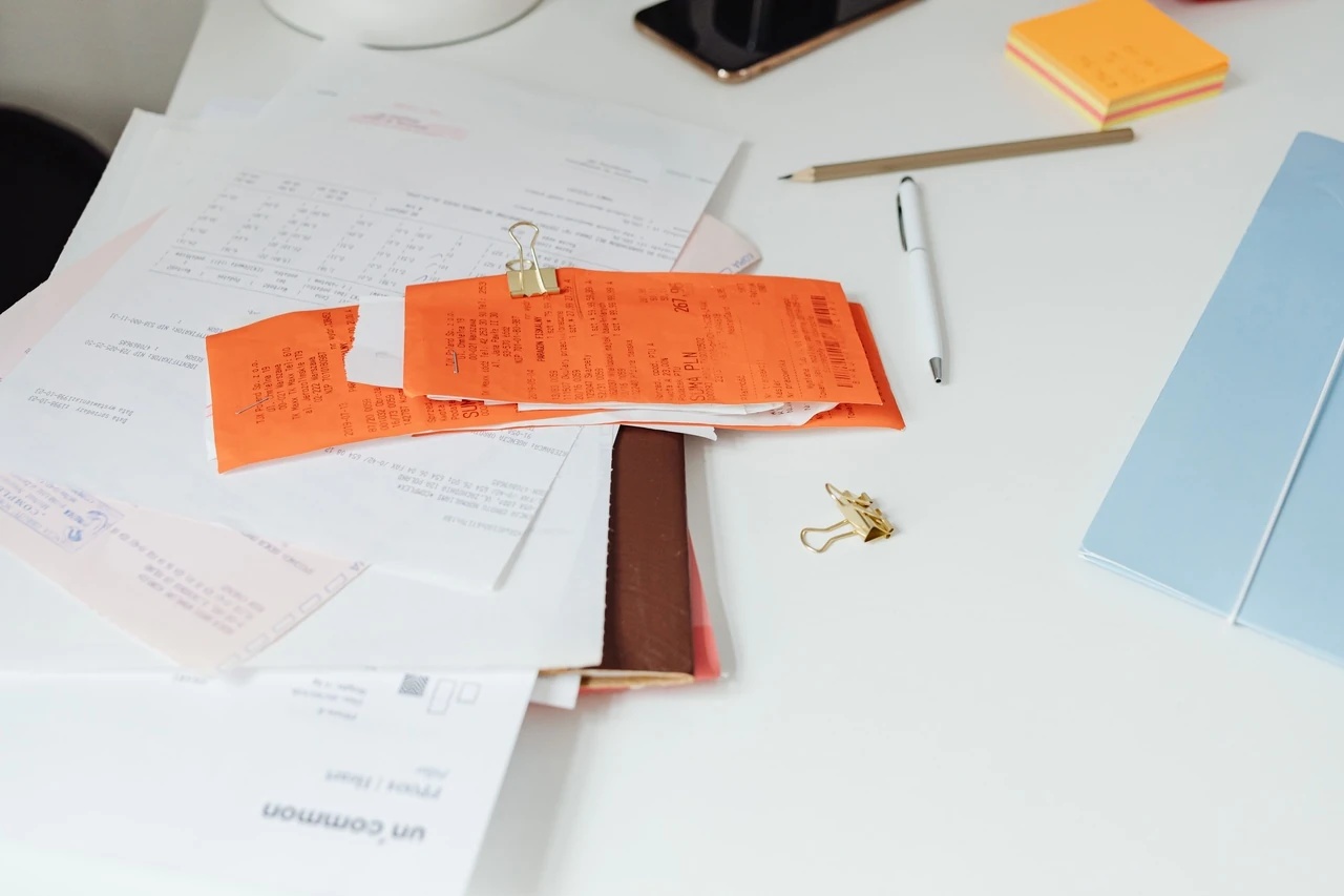 Papers, paper clips and a pencil scattered on a white desk