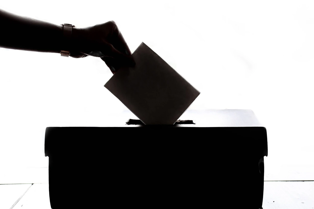 Silhouette of a hand dropping a ballot into a box