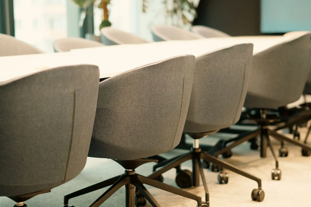 Rows of gray meeting chairs around a long white table