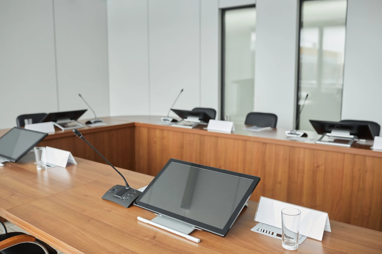 Board room table with microphones and tablets in front of each seat