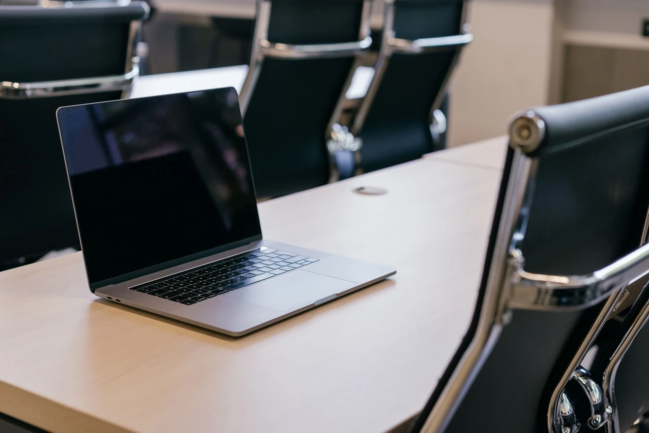 Laptop open on a conference table with office chairs