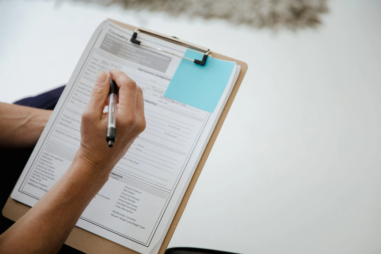 Hand filling in a form on a clipboard